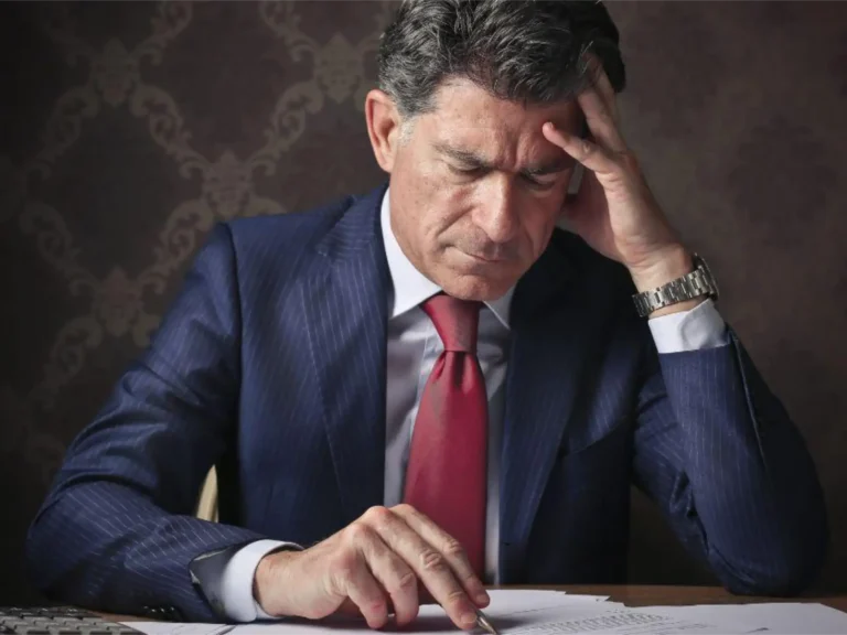 Business owner reviewing paperwork at a desk, appearing overwhelmed